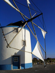 Typical Portuguese windmill from the central and southern regions in Sesimbra, Portugal. View of the cloth sails partially unwrapped from the masts.