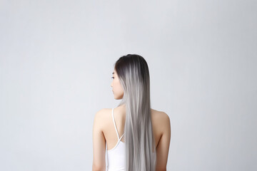 The rear view of a young woman with sleek, silver long hair, photographed in a studio with a white background and professional lighting. Generative AI.