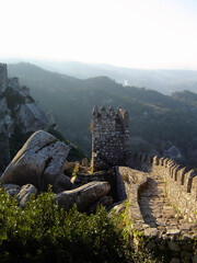 Medieval Castelo dos Mouros aka Castle of the Moors in Sintra, Portugal. Watchtowers and defensive walls climbing the ridge of the mountain with a view of the landscape