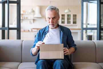 Mature man with frowning face receive wrong parcel, delivery post mistake - obrazy, fototapety, plakaty