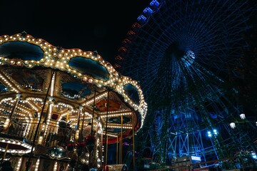 Vibrant scene of a carnival-style amusement park, illuminated by hundreds of colorful lights