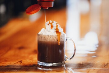 coffee being poured into a glass with ice cream and caramel on top