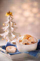 homemade cookies in a bowl on the background of a decorative Christmas tree, close-up, light background