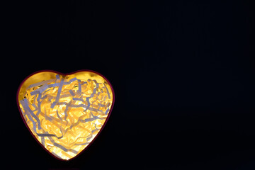 Corazón iluminado sobre fondo negro, concepto del día de San Valentín. Espacio para texto al...