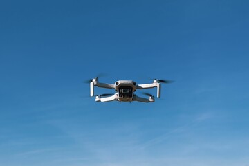 the small black and white drone is flying in the sky