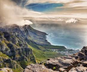 Papier Peint photo autocollant Montagne de la Table Aerial view of clouds rolling over Table mountain in Cape town, South Africa with copyspace. Beautiful landscape of green bushes and rocky terrain on misty morning, calming view of the ocean and city