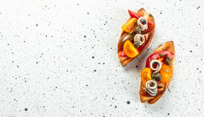 Toasted Bread with Anchovies and tomatoes on a light background. Long banner format. top view