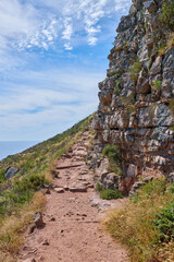 A footpath on mountain in Cape Town, South Africa. Outdoor trail for exploring in a peaceful, breathtaking cliff on Lions Head. Quiet nature in harmony, lush green growth on a peaceful, sunny morning