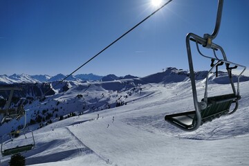 Empty chair of a ski lift in the snowy mountainous landscape on a sunny day