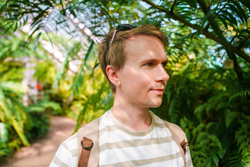 A young man in a tropical greenhouse in a botanical garden