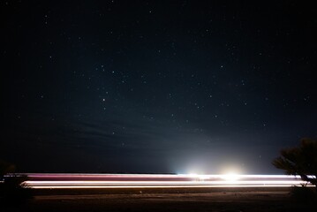 Long exposure of the light trains of a car driving down a dark road at night