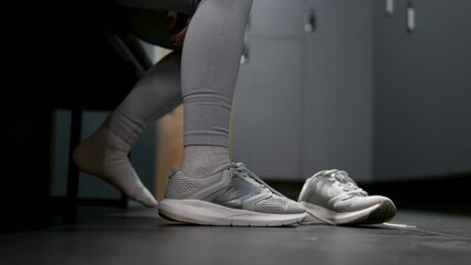 preparing for sports activities young teenage girl putting on sneakers in gym locker room gray tracksuit beautiful figure chic body close-up putting on shoes getting ready self-care. healthy lifestyle