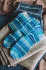 Hand knitted blue socks with sweater and jeans. Concept for handmade and hygge slow life.
