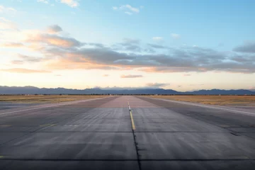 Schilderijen op glas Clouds bathed in the warm glow of the setting sun, overlooking the expansive and empty airport runway © Radmila Merkulova