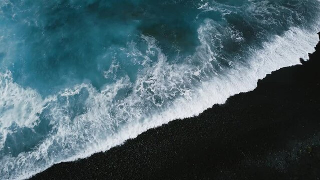 Horizontal aerial 4k footage of black sand volcanic beach  and big and strong waves in ocean -  Lanzarote, Canary Islands. Waves in blue ocean from above with cliff