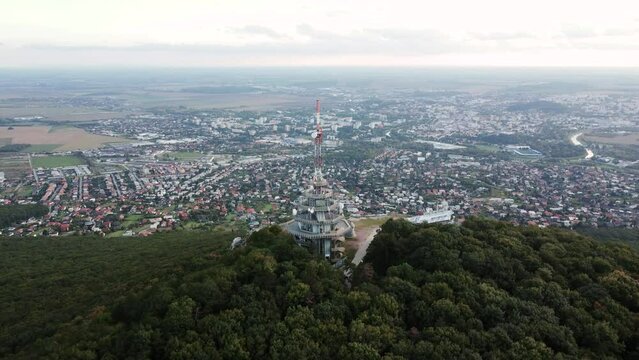 4k aerial footage of transmitter tower on Zobor Hill in Nitra - Slovakia.  Flight by drone over the hill and large city near forest.