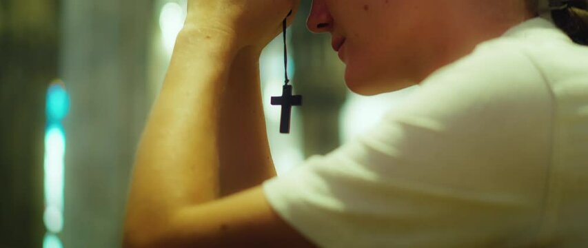 Woman parishioner prays in cathedral church close-up. A sincerely believing adult girl talking to God.