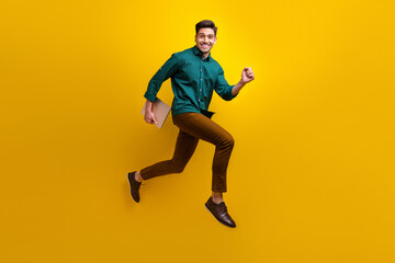 Fototapeta na wymiar Photo of cheerful nice man wear stylish clothes run hold netbook macbook isolated on yellow color background