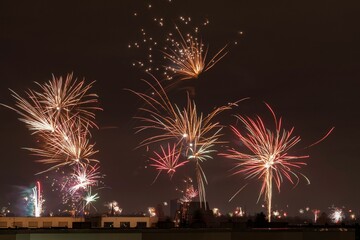 Illuminated night sky filled with vibrant fireworks explode above a cityscape of buildings