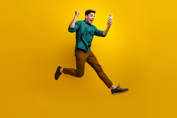 Fototapeta na wymiar Photo of overjoyed cheerful man dressed stylish clothes going running reading sms isolated on yellow color background