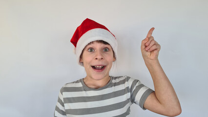 Cute little girl in Santa Claus Christmas hat is thinking New Year gift and holding finger up for new idea