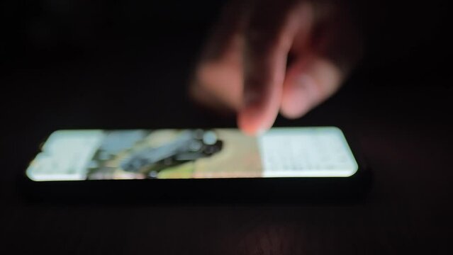 using the phone in a dark room, flipping through a photo of a defocused car
