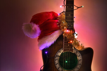 Guitar with hat and Christmas lights isolated with illuminated background - obrazy, fototapety, plakaty