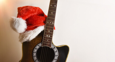 Guitar body with santa hat leaning on isolated white wall