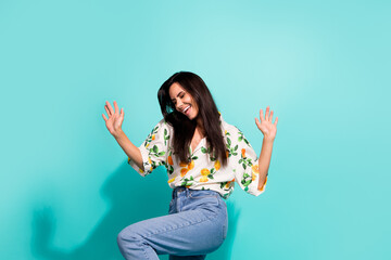 Photo of pleasant woman with long hairstyle dressed flower print blouse raising up palms having fun isolated on turquoise color background