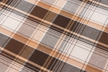 Close-up texture of brown and ivory checked tartan fabric in tilted view. Traditional Scottish...