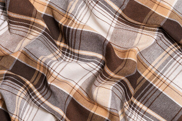 The texture of crumpled tartan fabric in brown and ivory colors. Background for your design