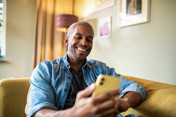 Smiling man holding smartphone at home