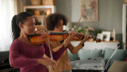 Mother and teenage boy playing violins at home