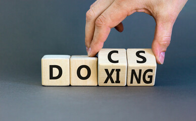 Docs or doxing symbol. Concept words Docs Doxing on wooden block. Beautiful grey table grey background. Businessman hand. Business docs or doxing concept. Copy space.