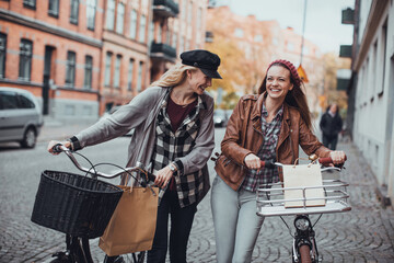 Two young women walking in the city with bikes
