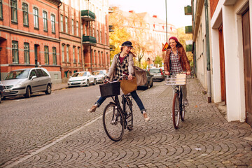 Obraz premium Two young women riding bicycles in the city