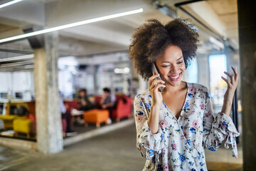 Young businesswoman talking on a smartphone gesturing in the office