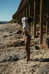 Fototapeta na wymiar A beautiful, sporty, slender brunette is posing by the sea on the beach.