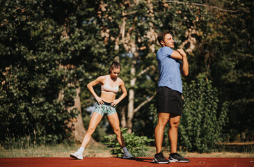 Naklejka premium Motivated couple enjoys active outdoor workout in the park. They inspire with their fit bodies, persistence, and positive mindset. Training outdoors provides fresh air and natural environment.