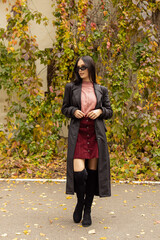 Young woman in black sunglasses, leather raincoat and pink turtleneck. Natural. Attractive woman in park. Youth fashion. In full growth © Svetlana