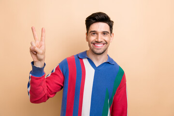 Photo of satisfied glad young person beaming smile arm fingers demonstrate v-sign isolated on beige color background