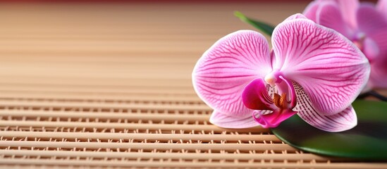 Close up of a pink orchid on a mat made of bamboo