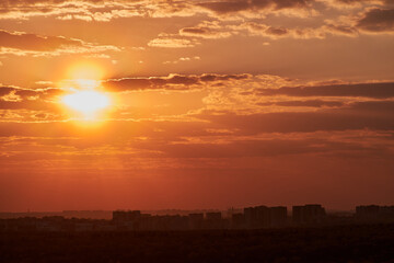 The setting sun casts a warm glow over the city, as the sky turns shades of orange and red.