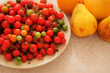 Cherry tomatoes and pears in a clay beige plate. Red farm tomatoes in rustic bowl.
