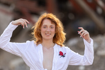 A young woman with red hair poses in a white shirt
