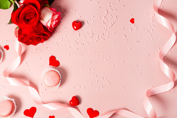 Modern valentine's day card - roses, macaroons and valentine decor on pink background top view, copy space for text