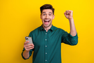 Photo of crazy cheerful glad man wear trendy clothes raise hand fist rejoice success luck isolated on yellow color background