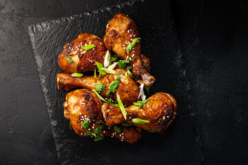 Chicken drumsticks with sesame seeds, Asian cooked chicken on a black background top view