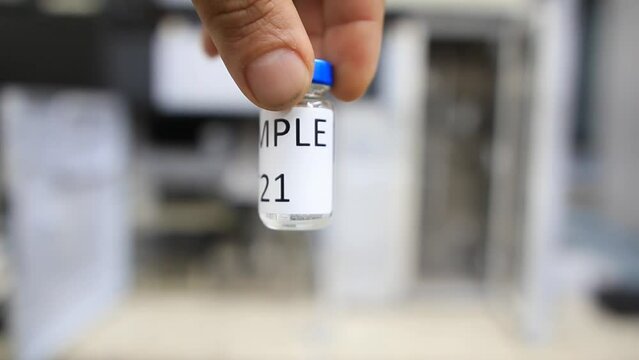 A man holds a vial with a sample of water to perform trace analysis looking for pesticides, organic solvents and heavy metals 
