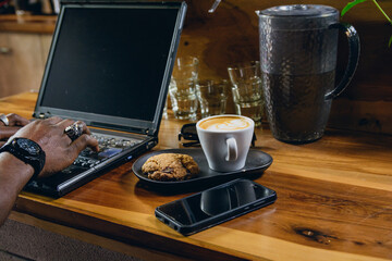Back view of unrecognizable freelancer black man working on laptop on restaurant counter